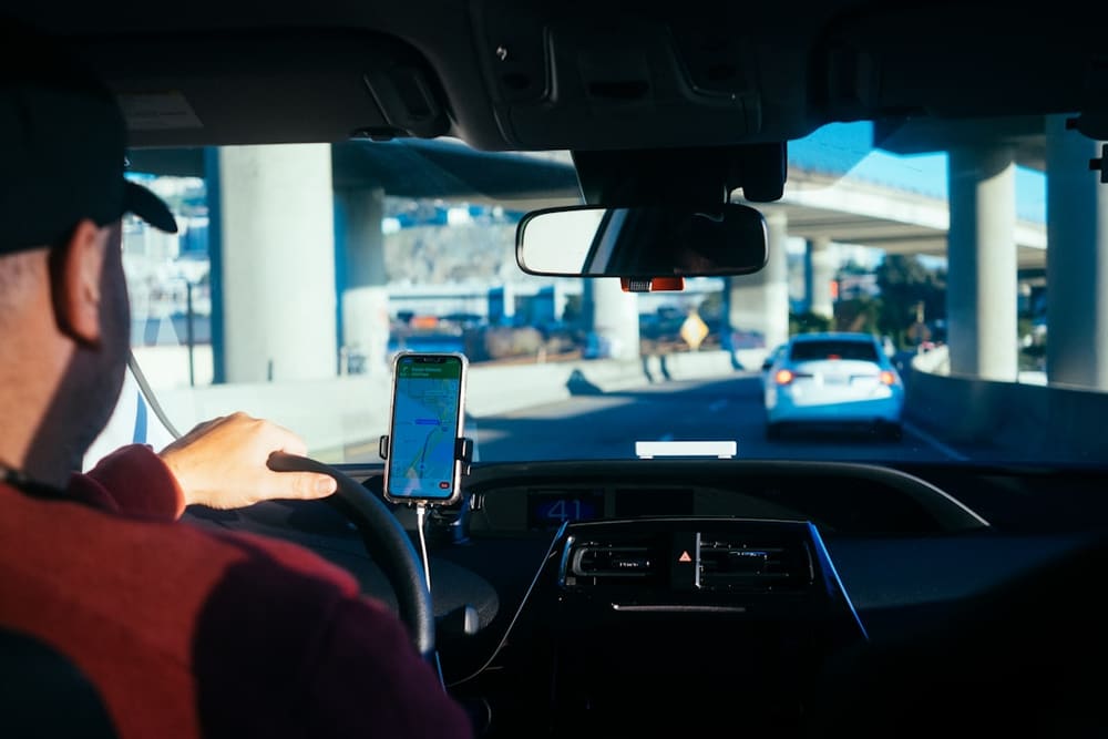 Persoon met een smartphone in de hand in een auto