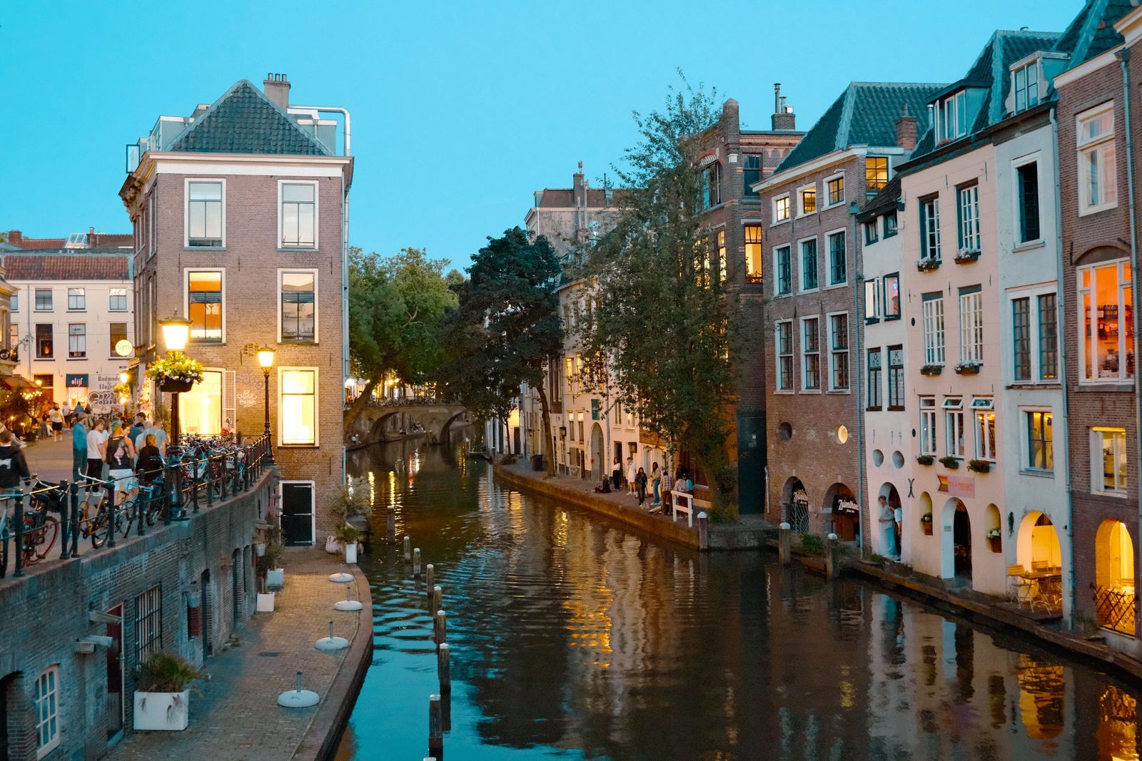 Utrechtse gracht bij avondlicht, met historische panden, fietsen en mensen op de kade