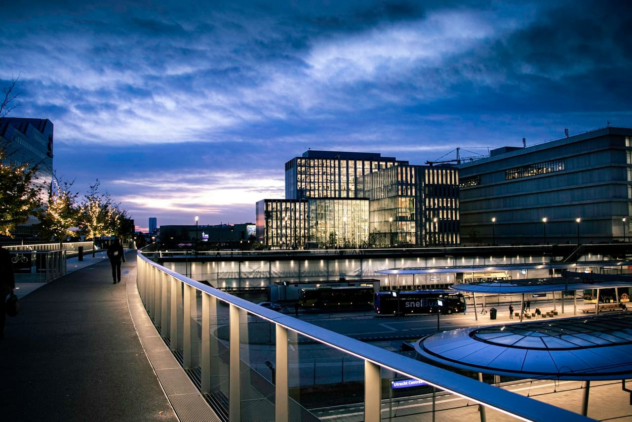 Utrecht Centraal-gebied bij nacht, verlichte gebouwen onder een paarse avondlucht